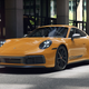 A Bahama Yellow 2023 Porsche 911 Carrera T is parked in front of a building.